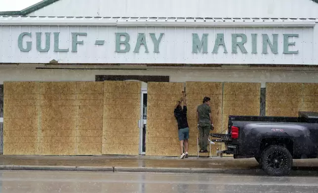 Doan Vu, left, and Luan Nguyen, right, board up windows as they prepare for Beryl's arrival, Sunday, July 7, 2024, in Palaciios, Texas. Texas officials are telling coastal residents to expect power outages and flooding as Beryl was forecast to regain hurricane strength before making landfall early Monday. (AP Photo/Eric Gay)