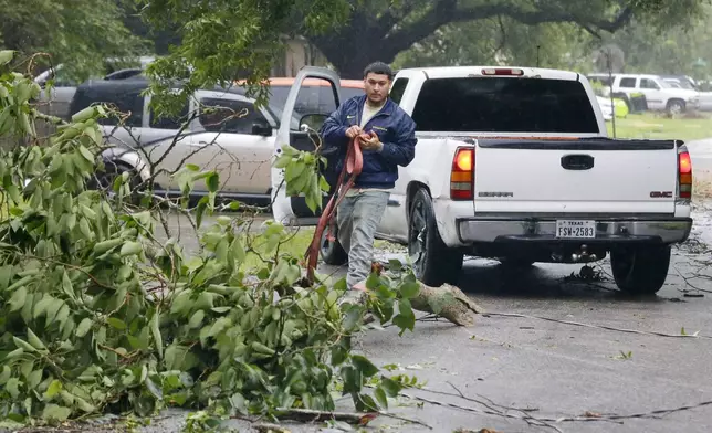 William Ruiz uses a tow strap and his pick-up truck to remove a downed tree branch from the middle of the street in his neighborhood during a lull as the eye of hurrican Beryl passes through Monday, July 8, 2024, in Rosenberg, Texas. (AP Photo/Michael Wyke)