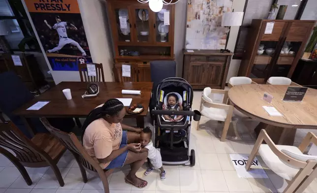 Houston resident Ashley Doyle and her children, Kaysen and Jayce, spend time at Gallery Furniture, which is being used as a temporary shelter, to cool off and and have a meal, Tuesday, July 9, 2024, in Houston. The effects of Hurricane Beryl left most in the area without power. (AP Photo/Eric Gay)