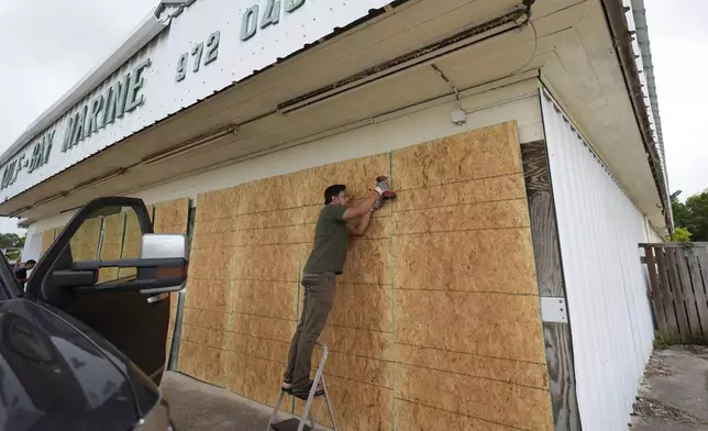 Luan Nguyen boards up windows as he helps prepare for Beryl's arrival, Sunday, July 7, 2024, in Palaciios, Texas. Texas officials are telling coastal residents to expect power outages and flooding as Beryl was forecast to regain hurricane strength before making landfall. Landfall was expected early Monday. (AP Photo/Eric Gay)