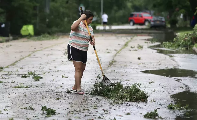 Resident Isabel Perez rakes up downed tree branches from the street outside of her home during a lull in the wind and rain as Tropical Storm Beryl passes Monday, July 8, 2024, in Rosenburg, Texas. Hurricane Beryl has been downgraded to a tropical storm after sweeping into Texas as a Category 1 storm with heavy rains and powerful winds. (AP Photo/Michael Wyke)