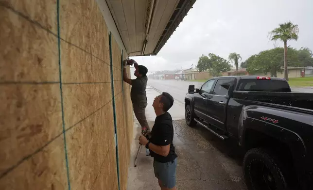 Doan Vu, right, and Luan Nguyen, left, board up windows as they prepare for Beryl's arrival, Sunday, July 7, 2024, in Palaciios, Texas. Texas officials are telling coastal residents to expect power outages and flooding as Beryl was forecast to regain hurricane strength before making landfall early Monday. (AP Photo/Eric Gay)