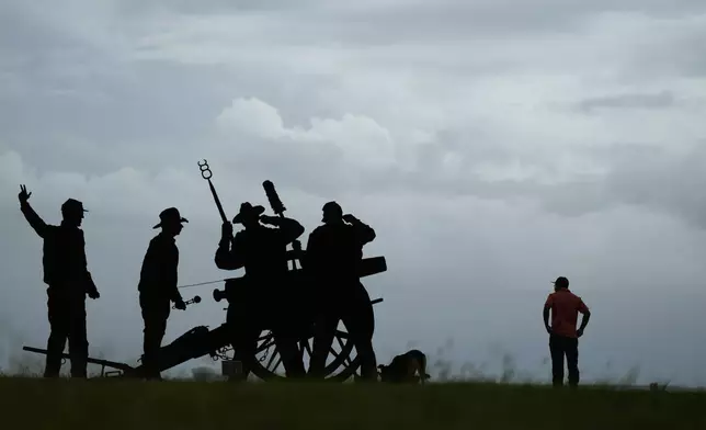 A man walks his dog near a Confederate Artillery Battery display as he watches storm clouds roll in ahead of Beryl, Sunday, July 7, 2024, in Port Lavaca, Texas. (AP Photo/Eric Gay)