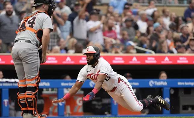 Minnesota Twins' Manuel Margot dives to score off a two-run double during the third inning of a baseball game against the Detroit Tigers, Tuesday, July 2, 2024, in Minneapolis. (AP Photo/Abbie Parr)