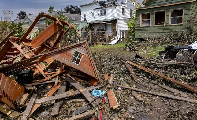 A destroyed children's playhouse rests behind the heavily damaged homes owned by landlord and owner Richard Secor, on Henry Street in South Rome, N.Y., Tuesday, July 23, 2024, following an EF2 tornado that touched down in the population center one week earlier. Residents are vowing to rebuild. But some of the damage was so severe that the path forward is uncertain for many in this old manufacturing city, where people are more accustomed to digging out from snowstorms than from piles of rubble. (AP Photo/Craig Ruttle)