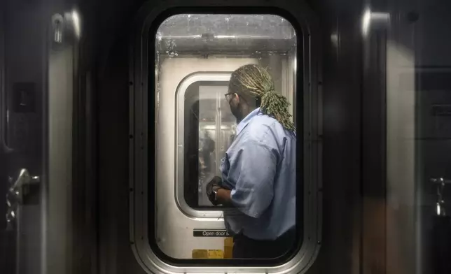 FILE - Conductor Desmond Hill checks on passengers from his crew cab as he works the N subway line from Brooklyn's Coney Island to Queen's Astoria-Ditmars neighborhoods, Aug. 13, 2021, in New York. Reports of crime against transit workers and passengers have been rising since the pandemic erupted in 2020, when millions of Americans suddenly avoided subways and buses. Their exodus left transit workers more isolated and vulnerable to attacks.(AP Photo/John Minchillo, File)