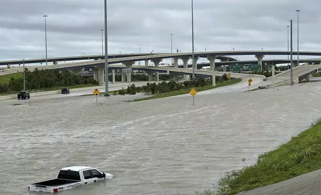 A vehicle is stranded in high waters on a flooded highway in Houston, on Monday, July 8, 2024, after Beryl came ashore in Texas as a hurricane and dumped heavy rains along the coast. (AP Photo/Juan A. Lozano)