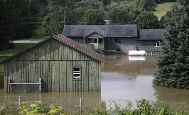 Water floods the lower level of homes, Thursday, July 11, 2024, in Waterbury, Vt. (AP Photo/Hasan Jamali)