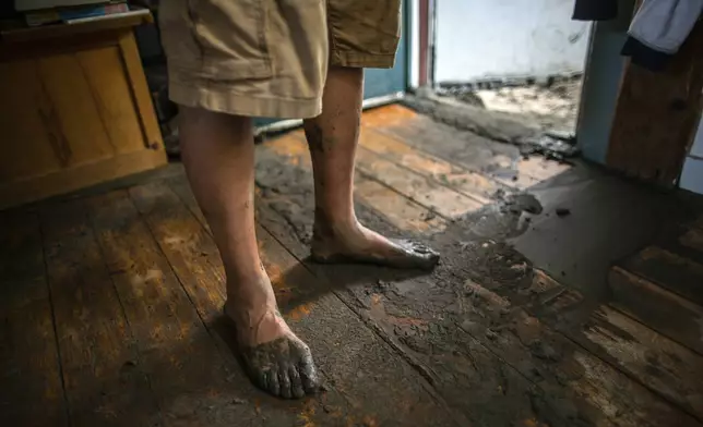 A resident, with muddy feet, stands in his damaged home following flooding caused by the remnants of Hurricane Beryl, Thursday, July 11, 2024, in Plainfield, Vt. (AP Photo/Dmitry Belyakov)