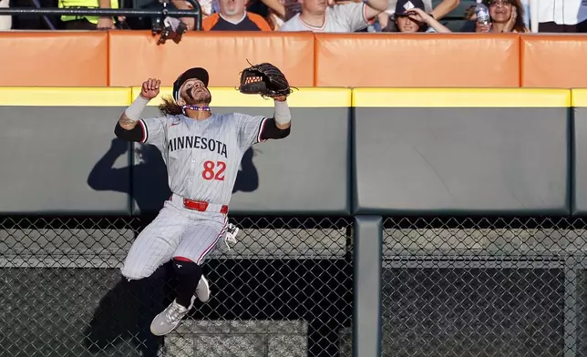 Minnesota Twins' Austin Martin (82) goes up against the left field wall in a vain attempt to catch a two-run home run hit by Detroit Tigers' Javier Baez during the seventh inning of a baseball game Saturday, July 27, 2024, in Detroit. (AP Photo/Duane Burleson)