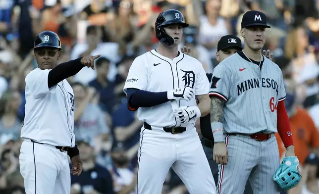 Detroit Tigers' Colt Keith, center, with third base coach Joey Cora, left, and Minnesota Twins third baseman Jose Miranda (64) after hitting an RBI-triple during a baseball game, Saturday, July 27, 2024, in Detroit. (AP Photo/Duane Burleson)