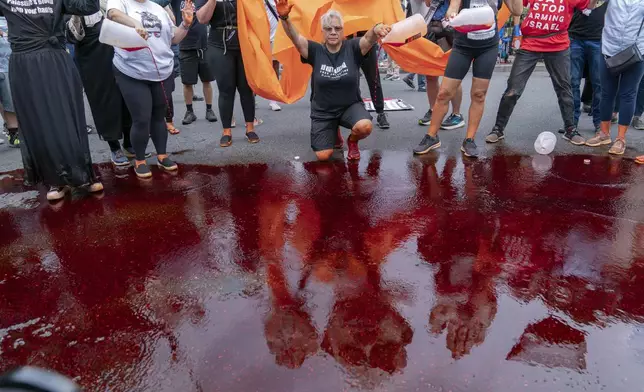 Demonstrators pour red liquid on the asphalt as they protest the visit of Israeli Prime Minister Benjamin Netanyahu to the White House during a rally at Lafayette Park, Thursday, July 25, 2024, in Washington. (AP Photo/Jose Luis Magana)