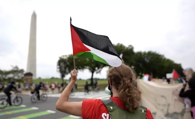 A demonstrator waves a Palestinian flag near the Washington Monument during a protest against the visit of Israeli Prime Minister Benjamin Netanyahu to the White House during a rally, Thursday, July 25, 2024, in Washington. (AP Photo/Mike Stewart)