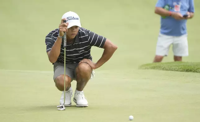 Charlie Woods eyes his putt on the 18th green during the first round of stroke play of the U.S. Junior Amateur Golf Championship, Monday, July 22, 2024, in Bloomfield Township, Mich. (AP Photo/Carlos Osorio)