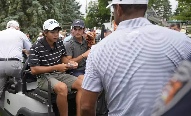 Charlie Woods, left, looks to his father Tiger Woods after finishing the first round of stroke play of the U.S. Junior Amateur Golf Championship, Monday, July 22, 2024, in Bloomfield Township, Mich. (AP Photo/Carlos Osorio)