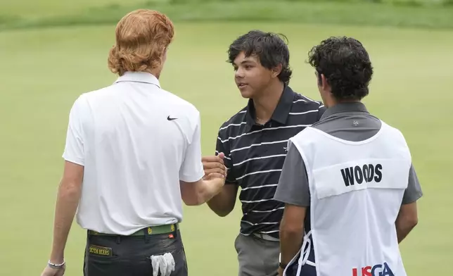 Charlie Woods shakes hands with Davis Ovard on the 18th green during the first round of stroke play of the U.S. Junior Amateur Golf Championship, Monday, July 22, 2024, in Bloomfield Township, Mich. (AP Photo/Carlos Osorio)