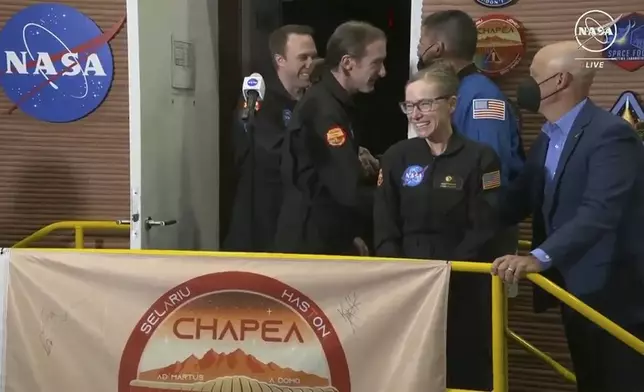 In this image made from video provided by NASA, the crew members of the first CHAPEA mission, Kelly Haston, third right, Ross Brockwell, center, Nathan Jones, left, and Anca Selariu, not in photo, emerge from their craft, Saturday, July 6, 2024, at Johnson Space Center in Houston, Texas. The four volunteers crew members spent more than 12 months inside NASA's first simulated Mars environment at Johnson Space Center in Houston, coming out of the artificial alien environment Saturday. (NASA via AP)