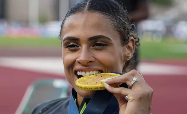 Sydney McLaughlin-Levrone bites down on her gold medal after winning the women's 400-meter hurdles final during the U.S. Track and Field Olympic Team Trials, Sunday, June 30, 2024, in Eugene, Ore. (AP Photo/Charlie Neibergall)