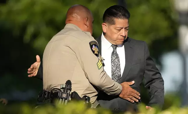 Former Uvalde Consolidated Independent School District police officer Adrian Gonzales, right, greets a Sheriff's deputy as he arrives at the Uvalde County Courthouse for a court appearance, Thursday, July 25, 2024, in Uvalde, Texas. (AP Photo/Eric Gay)