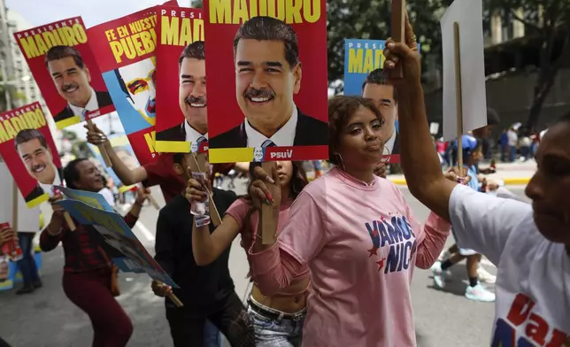 Supporters of Venezuelan President Nicolas Maduro carry posters of Maduro as they arrive early for Maduro's closing election campaign rally in Caracas, Venezuela, Thursday, July 25, 2024. The presidential election is set for July 28. (AP Photo/Cristian Hernandez)