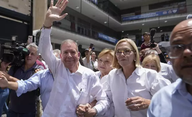 The opposition's presidential candidate Edmundo Gonzalez waves as he leaves the polling station with his wife Mercedes Lopez, center, and daughter Mariana after voting in presidential elections in Caracas, Venezuela, Sunday, July 28, 2024. (AP Photo/Matias Delacroix)