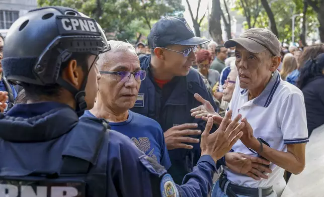 A voter talks to police guarding a polling station during the presidential election in Caracas, Venezuela, Sunday, July 28, 2024. (AP Photo/Cristian Hernandez)