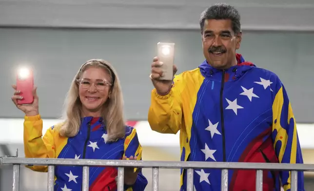 President Nicolas Maduro and First Lady Cilia Flores turn on their mobile phone flashlights after voting in the presidential elections in Caracas, Venezuela, Sunday, July 28, 2024. Maduro is seeking re-election for a third term. (AP Photo/Fernando Vergara)