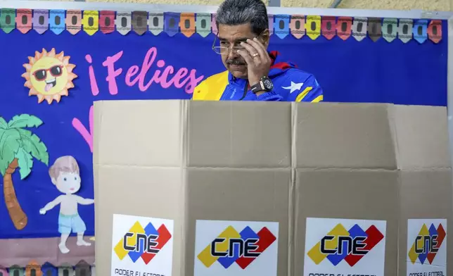 President Nicolas Maduro adjusts his glasses to mark his ballot for the presidential elections in Caracas, Venezuela, Sunday, July 28, 2024. Maduro is seeking re-election for a third term. (AP Photo/Fernando Vergara)