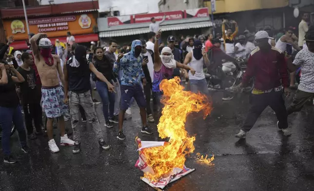 Protesters burn an election campaign poster of President Nicolas Maduro as they demonstrate against the official election results declaring him the winner the day after the presidential election in Caracas, Venezuela, Monday, July 29, 2024. (AP Photo/Matias Delacroix)