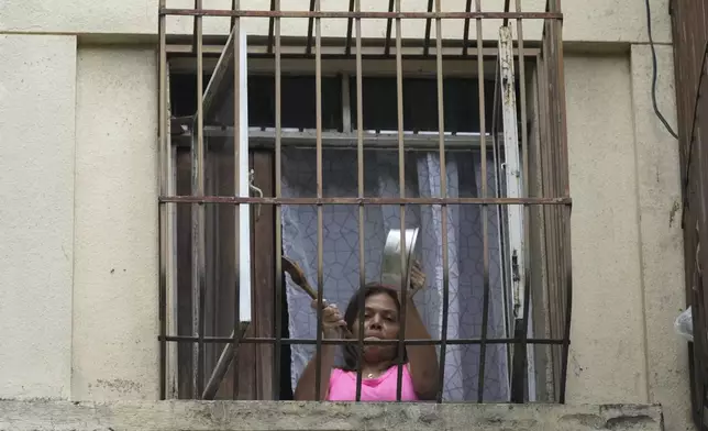 A resident bangs a pot to protest the day after the presidential election in Caracas, Venezuela, Monday, July 29, 2024. (AP Photo/Fernando Vergara)