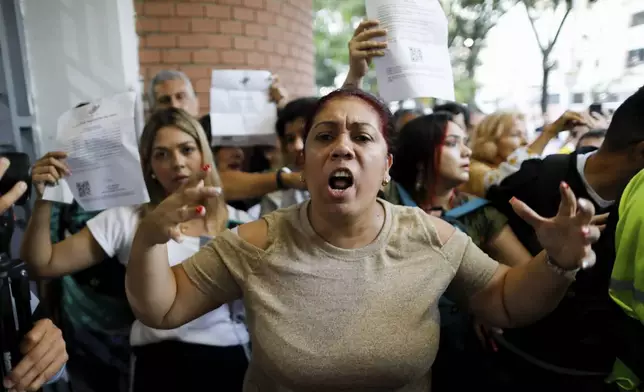 A government supporter, front, argues with opposition poll watchers who were denied access to the Andres Bello School polling center during the presidential elections in Caracas, Venezuela, Sunday, July 28, 2024. (AP Photo/Cristian Hernandez)