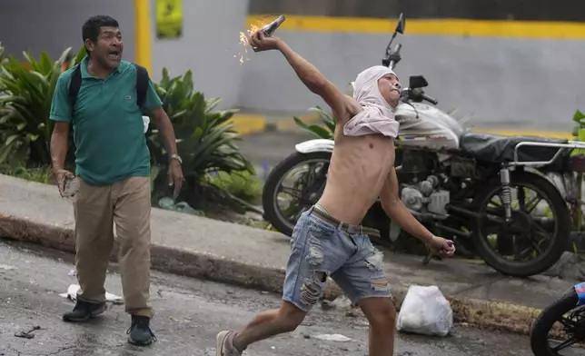 Residents throw objects at National Guards as they protest the official results the day after the presidential election in Caracas, Venezuela, Monday, July 29, 2024. (AP Photo/Fernando Vergara)