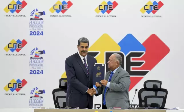 Venezuelan President Nicolas Maduro, left, receives certification from the President of the National Electoral Council (CNE) Elvis Amoroso that he won the presidential election, at the CNE in Caracas, Venezuela, Monday, July 29, 2024. (AP Photo/Matias Delacroix)