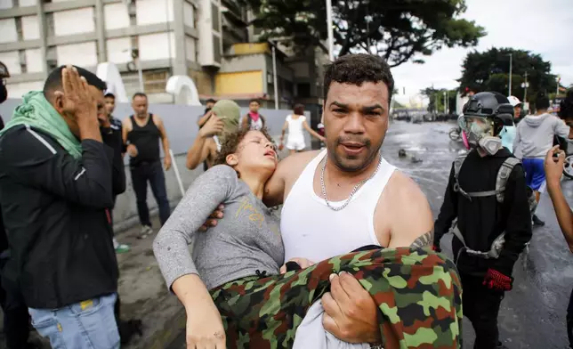 A man carries a protester affected by tear gas thrown by police during demonstrations against the official election results declaring President Nicolas Maduro's reelection, the day after the vote, in the Caria neighborhood of Caracas, Venezuela, Monday, July 29, 2024. (AP Photo/Cristian Hernandez)