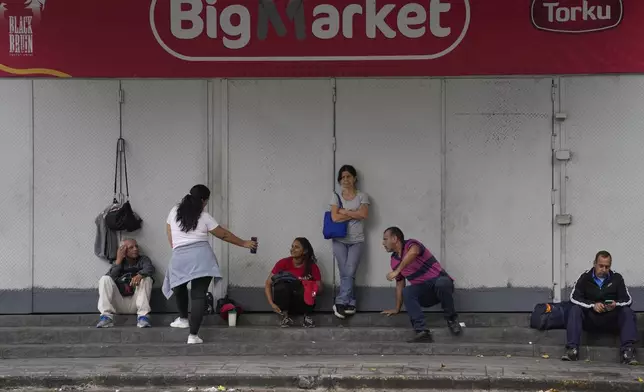 Grocery store workers wait for their employer to open for business in Caracas, Venezuela, Monday, July 29, 2024, the morning after the presidential election. (AP Photo/Matias Delacroix)