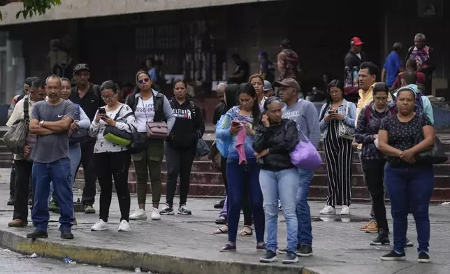 Commuters wait for a bus in the El Valle neighborhood of Caracas, Venezuela, Monday, July 29, 2024, the morning after the presidential election. (AP Photo/Matias Delacroix)