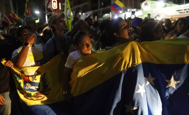 Opposition supporters hold a Venezuelan flag as opposition leader Maria Corina Machado and presidential candidate Edmundo Gonzalez attend their closing campaign rally in Caracas, Venezuela, Thursday, July 25, 2024. The presidential election is set for July 28. (AP Photo/Cristian Hernandez)