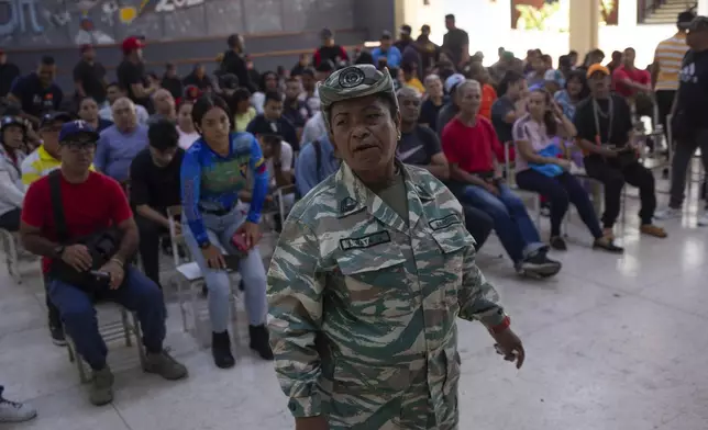 A pro-government militia member stands guard at a voting center during a rehearsal for the July 28 presidential election, in Caracas, Venezuela, Sunday, June 30, 2024. (AP Photo/Cristian Hernandez Fortune)