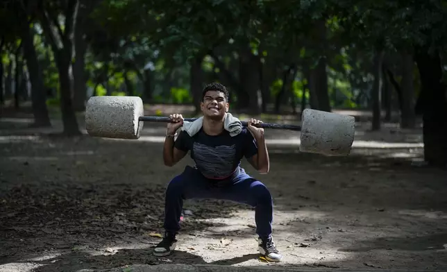 Daniel Fonseca, 15, lifts blocks of cement at a public gym set up at Los Caobos Park in Caracas, Venezuela, Tuesday, July 23, 2024. Venezuela is set to hold its presidential election on July 28. (AP Photo/Fernando Vergara)