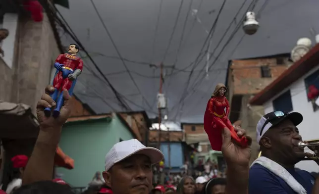 Action figures of Venezuelan President Nicolas Maduro and First Lady Cilia Flores are held up at a pro-government rally against U.S. sanctions on Venezuela in the Catia neighborhood of Caracas, Venezuela, Wednesday, June 5, 2024. Maduro is seeking a third term in the July 28 vote. (AP Photo/Ariana Cubillos)