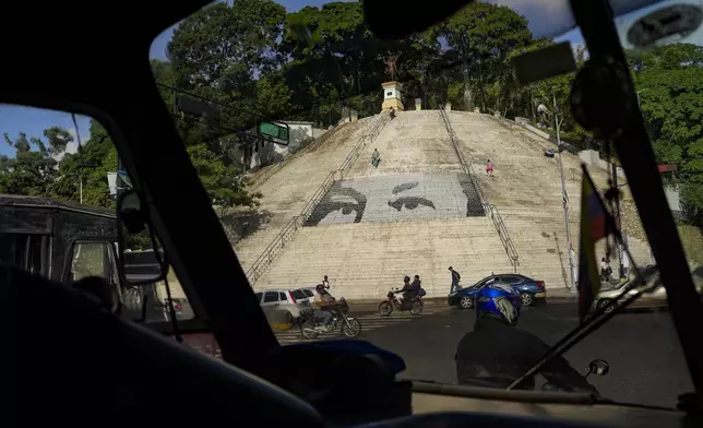 Seen through a bus window shield, a set of steps features a giant portrait of the eyes of the late President Hugo Chavez in Caracas, Venezuela, Friday, July 26, 2024. The presidential election is set for July 28. (AP Photo/Matias Delacroix)