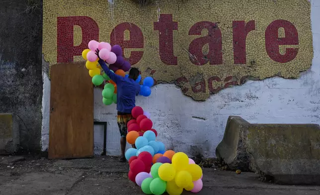 A resident removes balloons that decorated a wall in the Petare neighborhood of Caracas, Venezuela, Thursday, July 25, 2024, days before the July 28 presidential election. (AP Photo/Matias Delacroix)