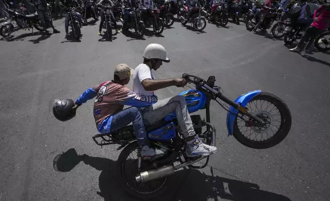 Motorcyclists do tricks as they rally before riding to the closing campaign event of Venezuelan President Nicolas Maduro who is seeking reelection in Caracas, Venezuela, Thursday, July 25, 2024. The presidential election is set for July 28. (AP Photo/Matias Delacroix)