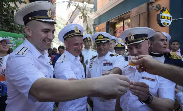 Russian crew members toast with a traditional Venezuelan drink during a welcoming tour by official authorities in La Guaira, Venezuela, after the Almirante Gorshkov frigate and Akademik Pashin oil tanker of the Russian Navy docked there, Tuesday, July 2, 2024. (AP Photo/Ariana Cubillos)