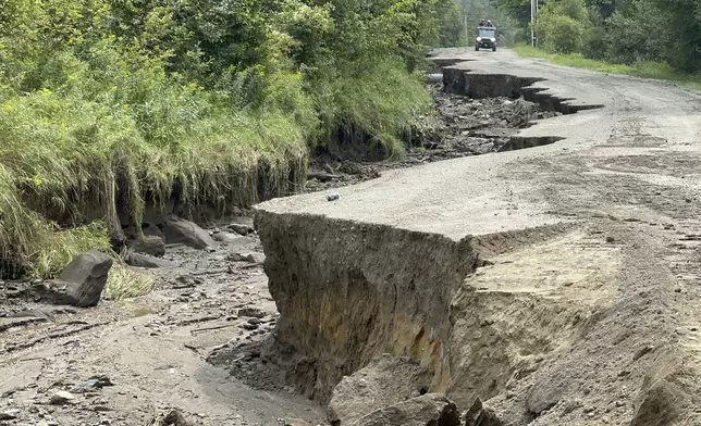 An all-terrain vehicle drives along a damaged roadway after flooding in Lyndonville, Vt., Tuesday, July 30, 2024. (AP Photo/Nick Perry)