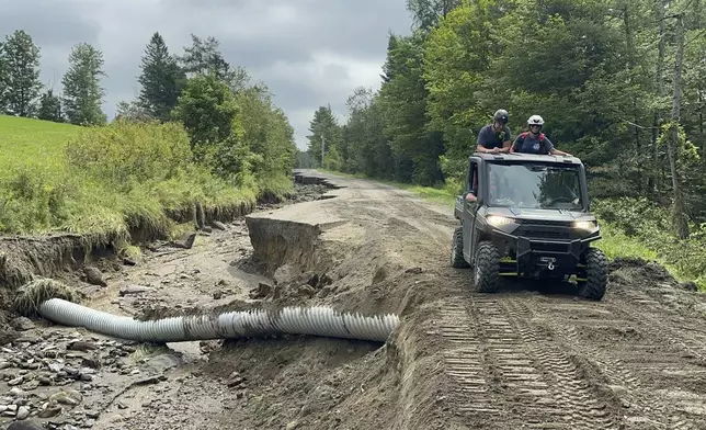 An all-terrain vehicle drives along a damaged roadway after flooding in Lyndonville, Vt., Tuesday, July 30, 2024. (AP Photo/Nick Perry)