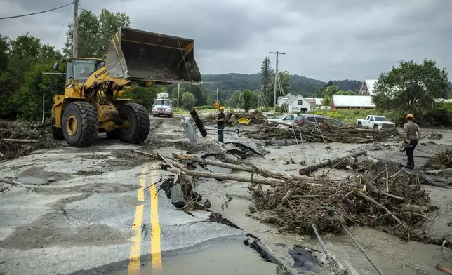 Workers clear debris amid flood damage in Lyndon, Vt., Tuesday, July 30, 2024. (AP Photo/Dmitry Belyakov)