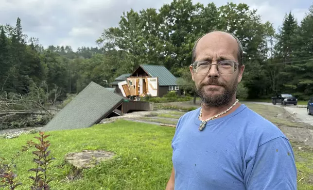 Jason Pilbin stands outside flood-damaged homes in Lyndonville, Vt., Tuesday, July 30, 2024. Pilbin helped neighbors evacuate early Tuesday morning before their house broke in half and then helped another neighbor exit her home during the heavy rains overnight, just weeks after witnessed a driver got swept away floodwaters there earlier this month. (AP Photo/Nick Perry)