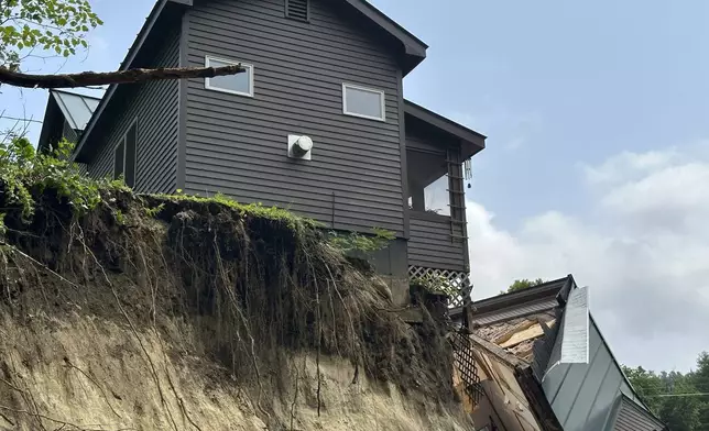 A damaged house sits on a ledge after flooding in Lyndonville, Vt., Tuesday, July 30, 2024. (AP Photo/Nick Perry)