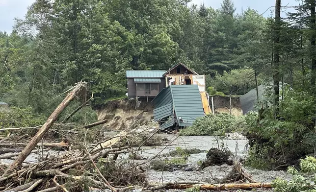 Trees and debris sit near a damaged home after flooding in Lyndonville, Vt., Tuesday, July 30, 2024. (AP Photo/Nick Perry)